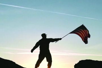 Military servicemember raises a flag to the sky